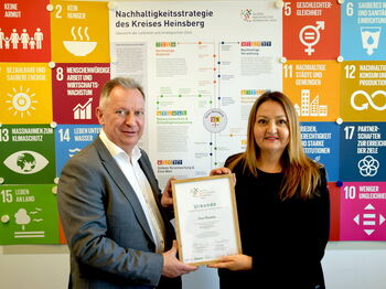 Landrat Stephan Pusch und Nachhaltigkeitsmanagerin Beyda Üner präsentieren die Urkunde „Kreis Heinsberg – Global Nachhaltige Kommune in Nordrhein-Westfalen“. Foto: Kreis Heinsberg